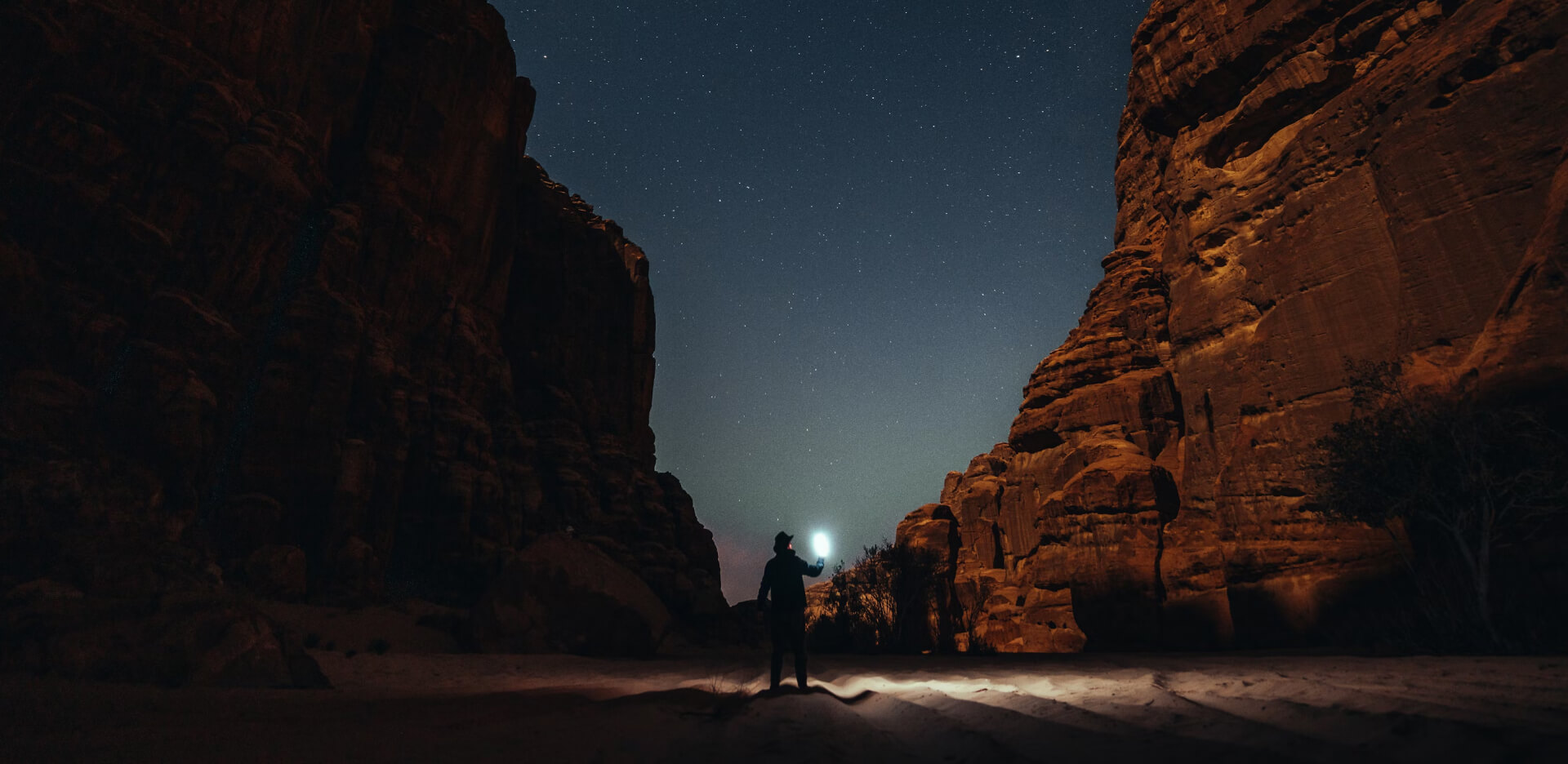 Night gorge, a man in a hat illuminates the area.