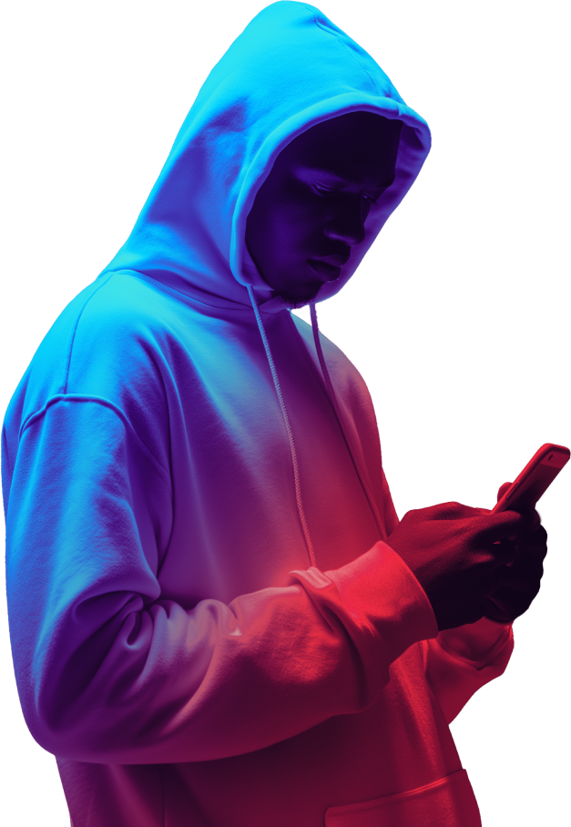 Young man in neon light in hoodie looking at phone screen.