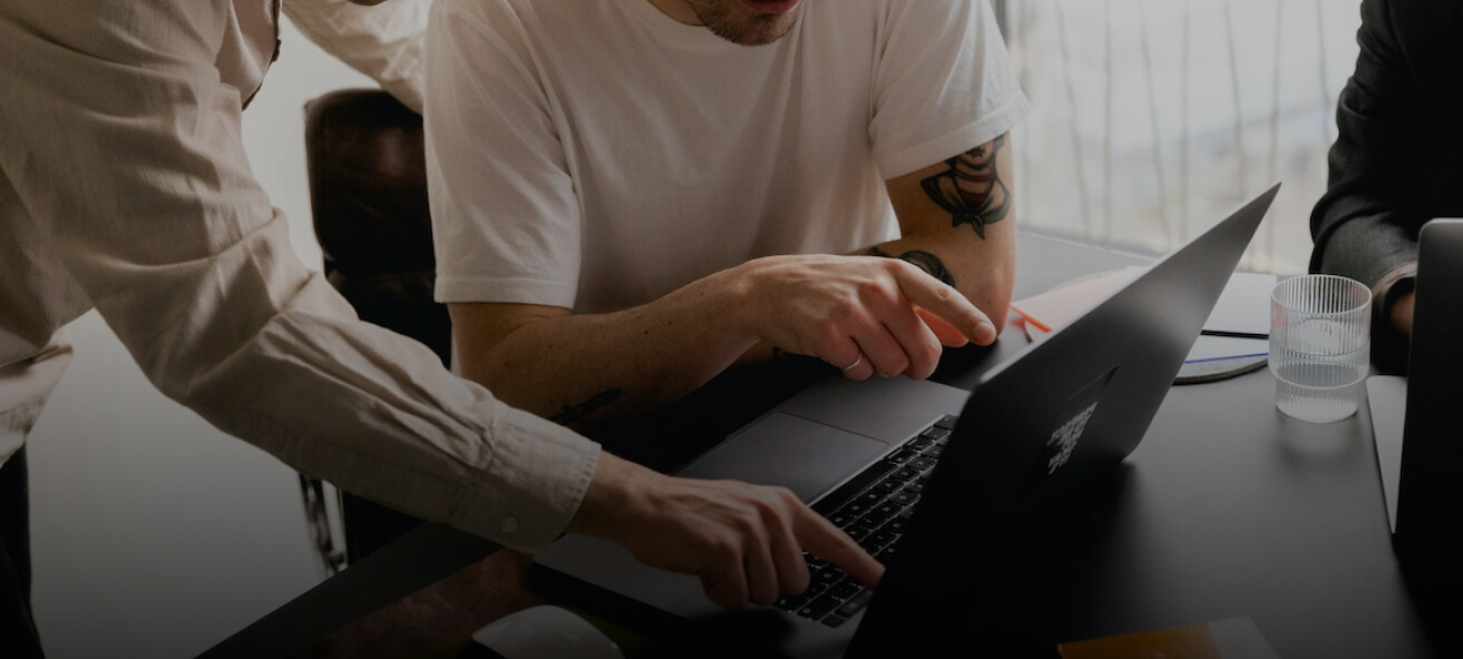 A photo of two guys looking at a laptop monitor screen.