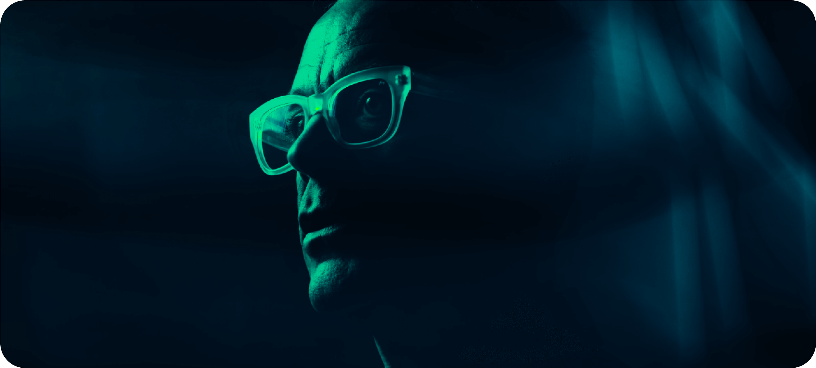 Green light on the face of a man with glasses.