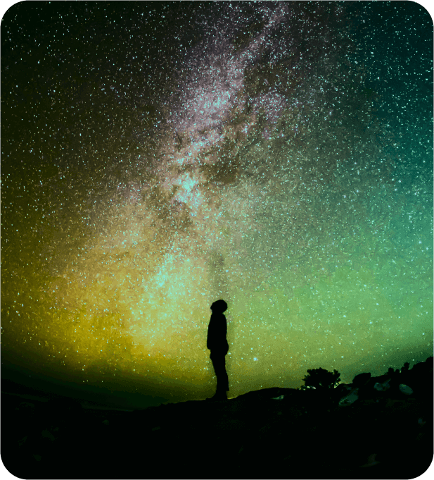 Silhouette of a man against the background of a bright multi-colored night sky.